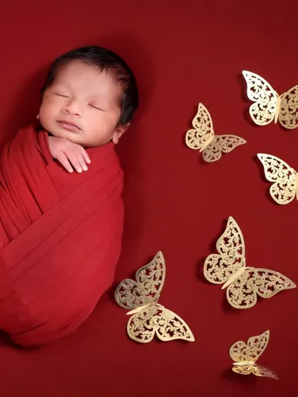Adding a touch of elegance with golden butterfly props. This image shows how we can enhance a simple setup to create a more magical and artistic newborn photo.