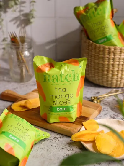 Product photography for Natch Snacks, styling their Thai Mango Slices in a natural, light-filled setting to emphasize the snack's wholesome appeal.
