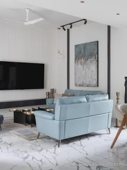 The living room is designed as an open floor plan to maximize visual volume. A gorgeous powder blue sofa takes center stage, complemented by abstract art and a statement coffee table.