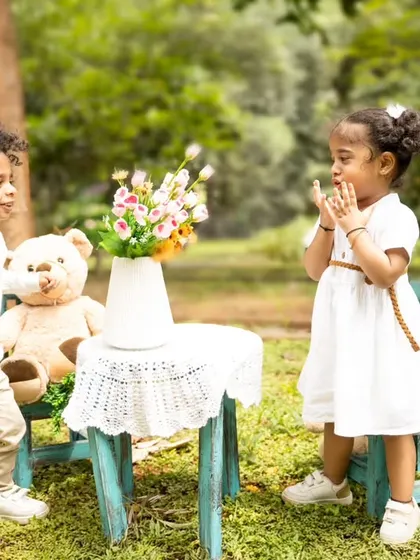 A candid moment of interaction between the twins during their outdoor teddy bear picnic.