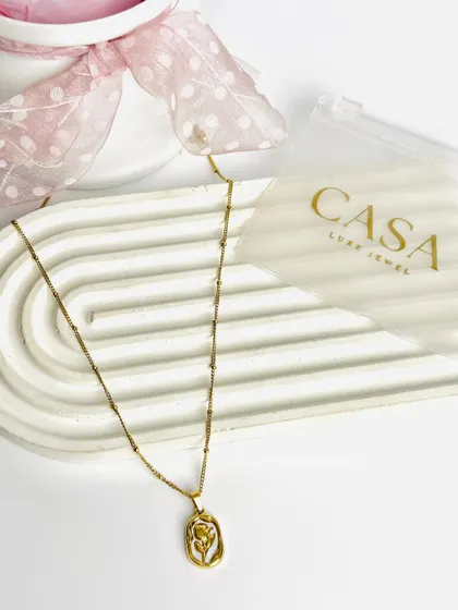 A gold pendant necklace with a floral design, shot in a simple, elegant flatlay. This highlights the product's details while maintaining a soft, feminine aesthetic.