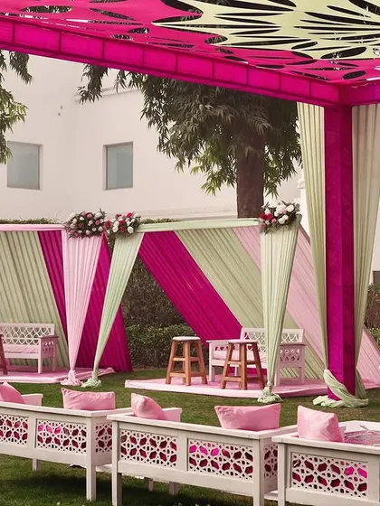 A seating area with alternating pink and mint green drapes, creating a fresh and vibrant look for a daytime Mehendi.