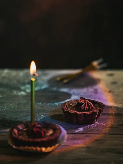 A birthday-themed shot with a lit candle in one of the chocolate tarts, creating a celebratory mood.