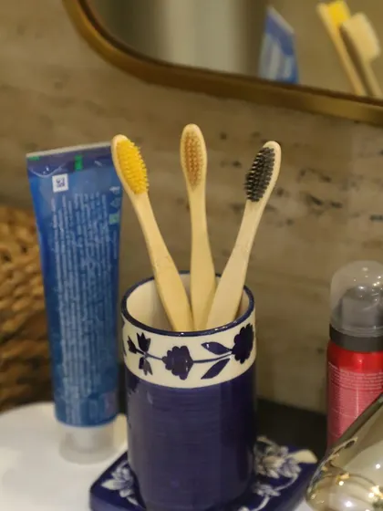 Our bamboo toothbrushes displayed in a bathroom setting, showing how they can easily replace plastic alternatives. We offer them with different colored bristles for easy identification.