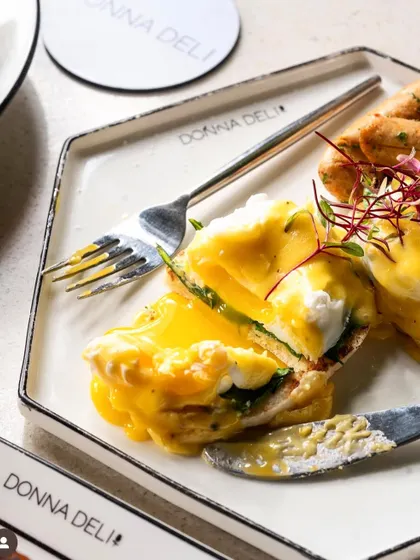 A classic eggs benedict, cut open to show the perfectly runny yolk. This is the ultimate "money shot" for any brunch menu.