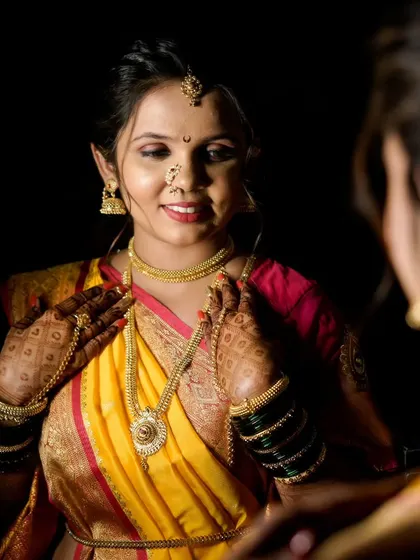 A moment of admiration as the bride looks at her reflection, checking her intricate gold jewelry against her vibrant yellow saree.