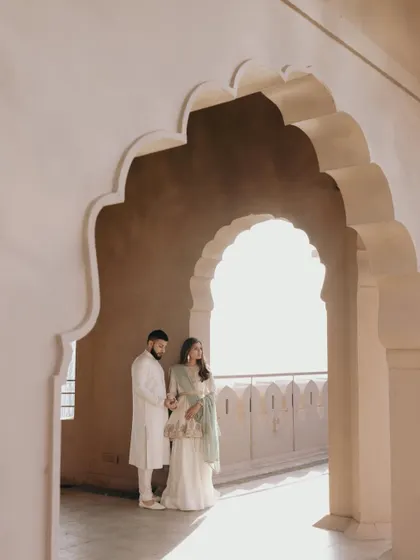 Amani and Tj framed perfectly within a traditional Rajasthani archway, with beautiful light creating a soft, romantic mood.