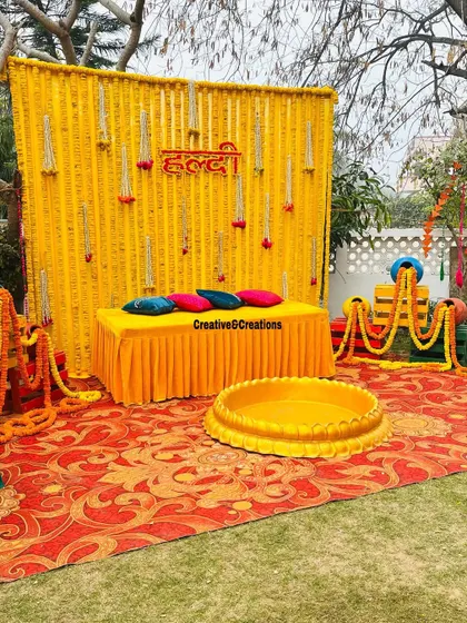 A complete Haldi ceremony setup in a garden. The marigold wall, seating area, and decorative elements are all perfectly coordinated for a beautiful traditional event.