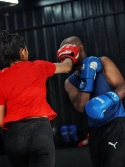 A female boxer practices her straight punches on a partner. The focus is on technique and accuracy.