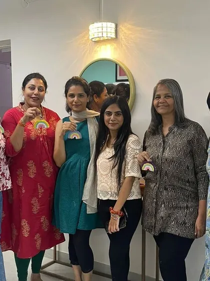 A group of friends proudly holding up the rainbow charms they made during a fun-filled workshop session.