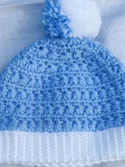 A close-up of the star stitch and fluffy pom-pom on the baby hat.