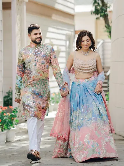 A lovely walking shot of a couple during their Mehndi ceremony. The groom's colorful kurta and the bride's pastel lehenga create a beautiful, vibrant picture of happiness.