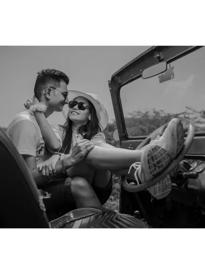 A fun, playful black-and-white shot of a couple relaxing in a jeep during their adventurous pre-wedding photoshoot.