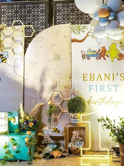 A creative photo backdrop with honeycomb accents, a neon '1', and beautiful balloon garlands in honey-inspired tones.