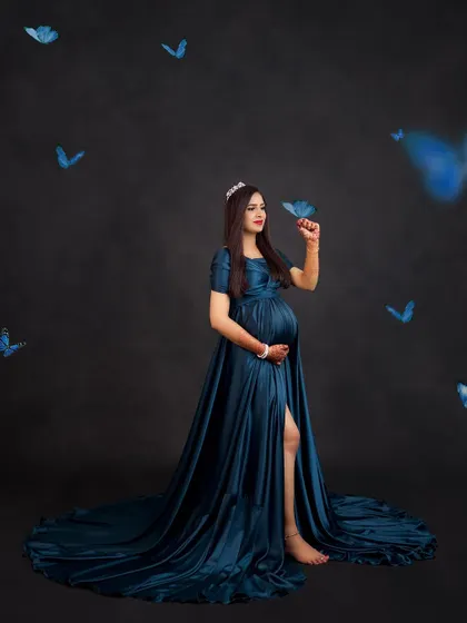 A whimsical portrait with blue butterflies seemingly fluttering around the mom-to-be in her beautiful teal gown.