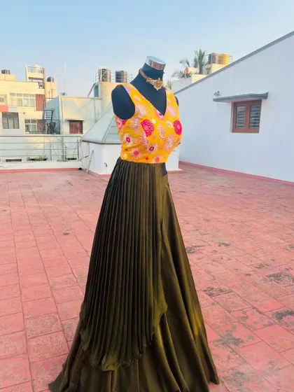 The unique design features an asymmetrical pleated drape over the skirt.