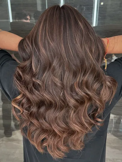 A view from the back of the chestnut brown balayage. You can see the seamless blend of highlights and the healthy shine of the hair after the coloring service.