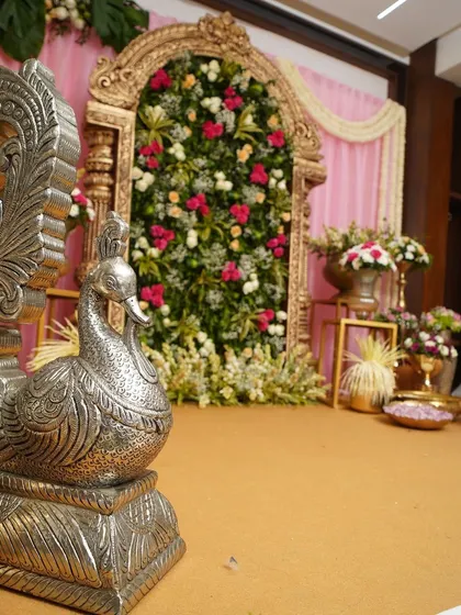 A silver peacock prop adds a touch of traditional elegance to this intimate celebration. Paired with a floral backdrop and brass vases, it helps create a rich, cultural atmosphere for a half-saree function.
