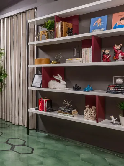 A custom open bookshelf in the lounge room provides a space to display personal treasures and books, adding character to the moody, fun space.