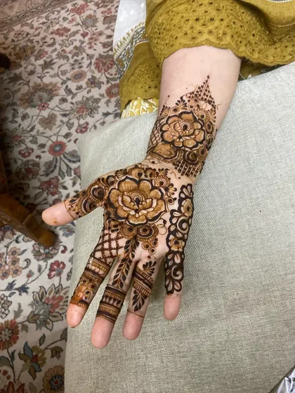 A bold Arabic design centered around large, shaded flowers on the back of the hand.