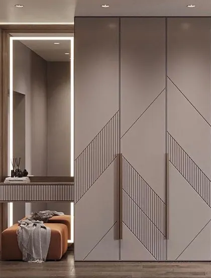 A beautiful wardrobe design with a chevron pattern and an integrated vanity table. The warm backlighting around the mirror creates a perfect spot for getting ready.