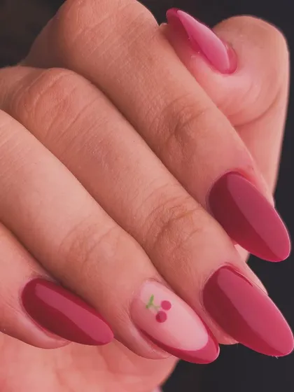 A sweet and simple design. This manicure features a deep red polish with a single accent nail adorned with a tiny, hand-painted cherry.