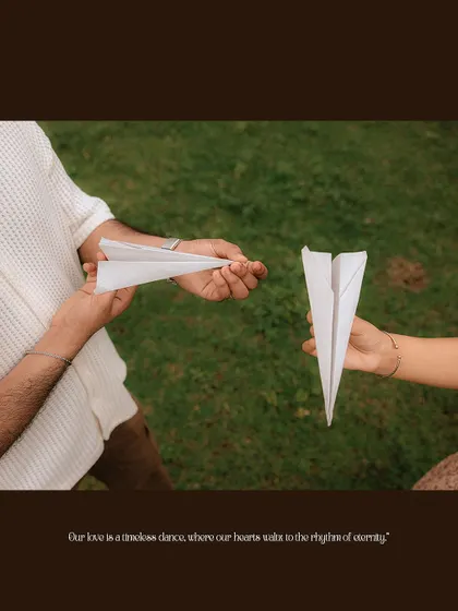 A close-up on the couple's hands holding paper airplanes, a symbol of their shared journey.