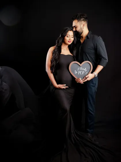 "Ready to POP!" This couple's portrait uses a cute heart-shaped sign to add a playful touch to their dramatic, dark-background maternity shoot.