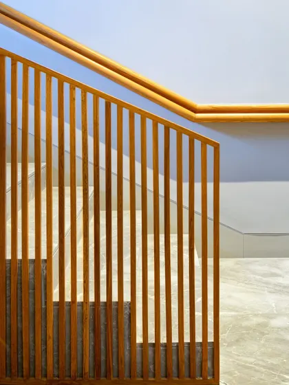 A slatted wooden screen acts as a semi-transparent partition for this staircase. It provides safety while creating a beautiful play of light and shadow, turning a functional element into a sculptural design feature.