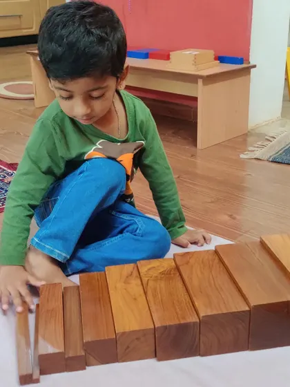 The Brown Stairs material helps children perceive differences in thickness. As this child arranges the prisms from thickest to thinnest, he is refining his visual perception and building his concentration.