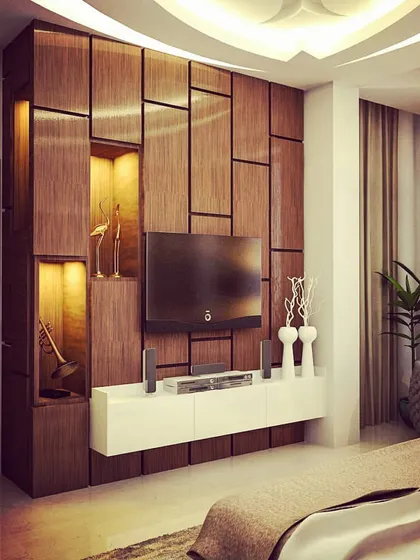A custom-designed TV and entertainment unit for a bedroom. The wall features a geometric wood panel design with built-in niches that are backlit to highlight decorative items.