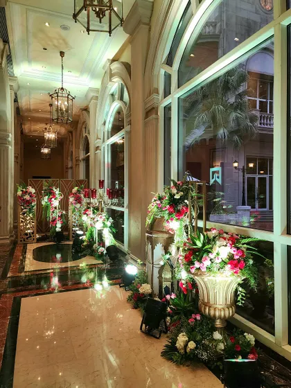 An elegant hallway at the Sufi Night event, lined with ornate floral arrangements in golden urns and traditional lanterns. This shows our commitment to transforming the entire event space.