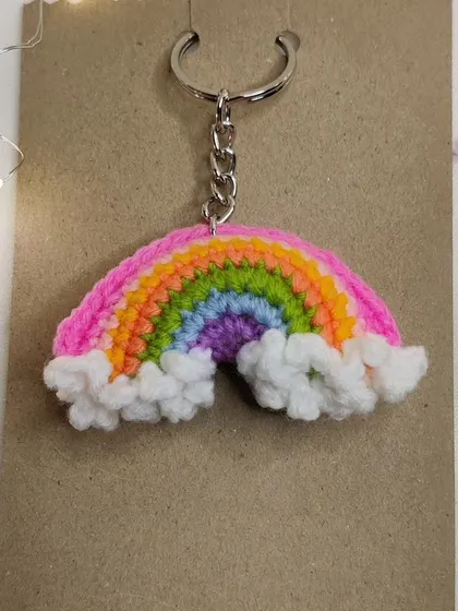 A vibrant rainbow keychain with fluffy white clouds, because who doesn't love carrying a rainbow around?