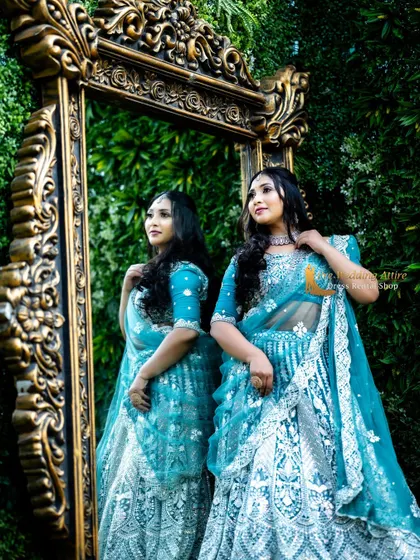 A creative shot using a mirror to reflect the sky blue embroidered lehenga. The intricate details are visible from both the front and back.