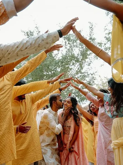 The groom is surrounded by his friends as they create an arch of hands for the couple to walk through during the Haldi ceremony. It's a beautiful symbol of their support and friendship.