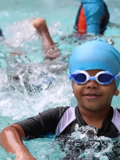 A young swimmer beams with confidence in the middle of a lesson. This look of accomplishment is what we strive for in every class we teach.