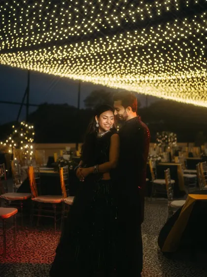 A romantic sangeet portrait under a sky of twinkling fairy lights. The couple is lost in each other's eyes, creating a moment of pure magic.