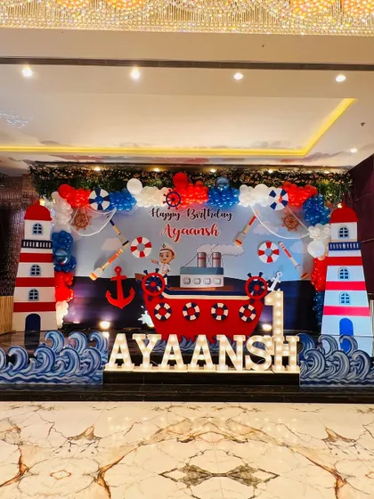 The full view of the nautical stage, with the baby's name in light-up letters and large lighthouse props.