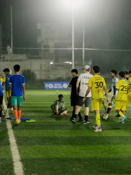 Players gather on the pitch under the floodlights during the VfB Stuttgart camp. The atmosphere of dedication and hard work continues even after the sun goes down.