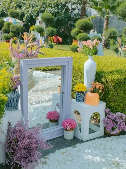 A mirrored sign with a sweet quote, placed amidst a garden of colorful flowers, adds a romantic and reflective touch to the Haldi decor.