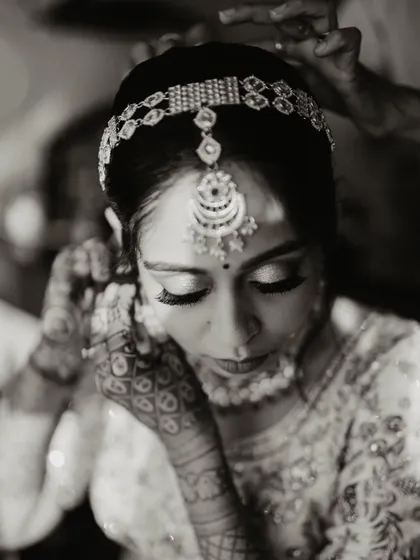 A black and white shot of the bride getting ready, focusing on the details of her jewelry and makeup.