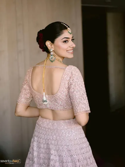 A beautiful back profile of the bride, showing off her elegant hairstyle and the delicate details of her blouse.