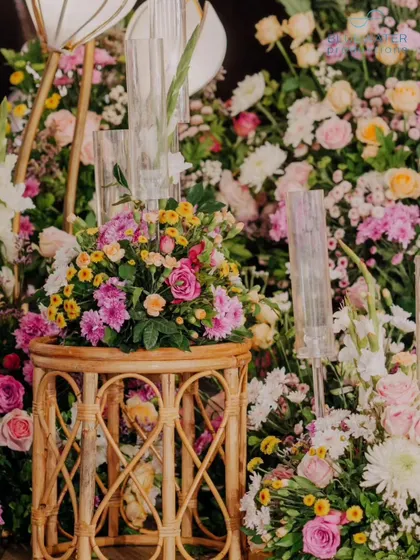 A beautiful detail shot of a cane side table and a lush floral arrangement.