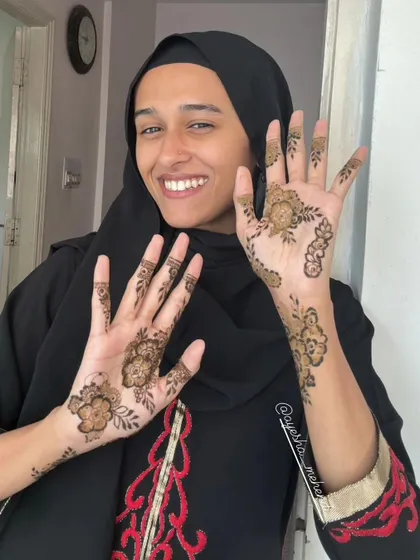 A lovely photo of a happy client and influencer showing off her simple and elegant floral henna. Her smile says it all.