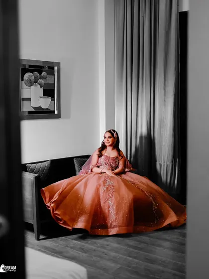 A unique portrait of Tanya seated on a sofa, the black and white edit with a pop of color on her gown creating a dramatic effect.