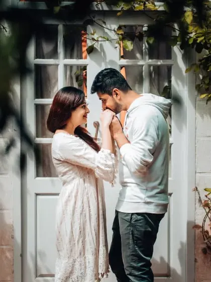 A tender kiss on the hand in front of a charming cottage. We focus on the small, affectionate gestures that define your relationship in our pre-wedding photography.