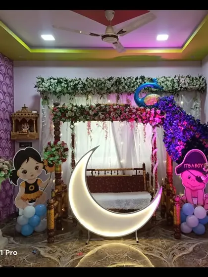 A baby shower decoration featuring a peacock made of flowers on a traditional swing. The lighted moon prop and character cutouts complete this elaborate home setup.