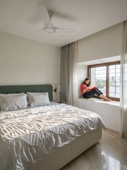 We used full-height curtains concealed in the ceiling to make the room feel taller. The combination of white paneled walls and soft fabrics creates a restful atmosphere.