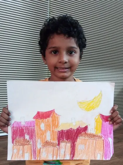 Myron, a 2nd standard student, drew this cityscape at night. He used oil pastels to create a warm, colorful scene with a crescent moon in the sky.