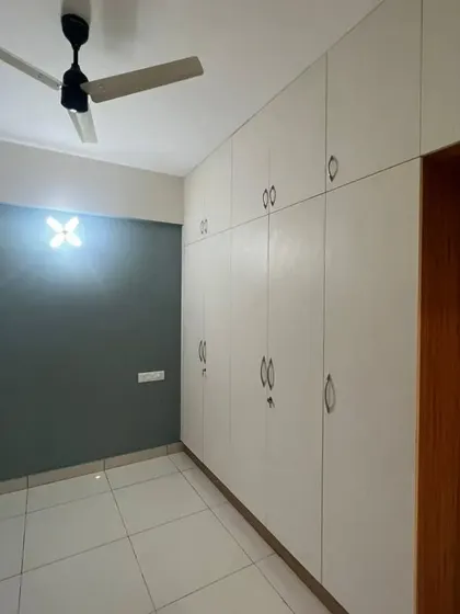 An empty bedroom with a full-wall wardrobe in a light laminate finish, demonstrating the clean and precise installation of our custom storage.